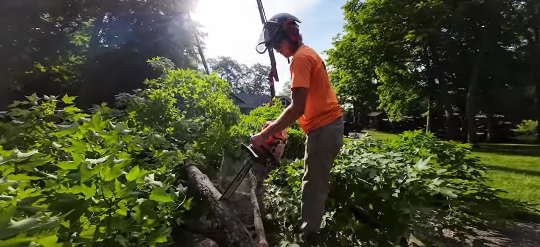 A man using a chainsaw to cut up a tree.