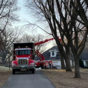 A dump truck is parked in front of a house for tree trimming.